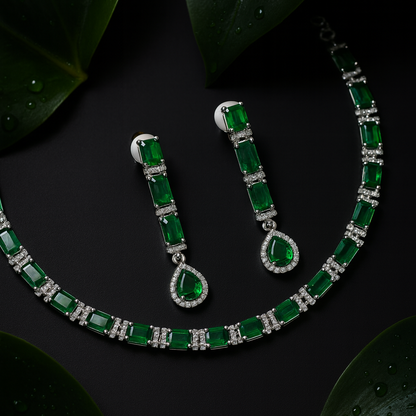 Green gemstone necklace and earrings on a dark surface with leaves.